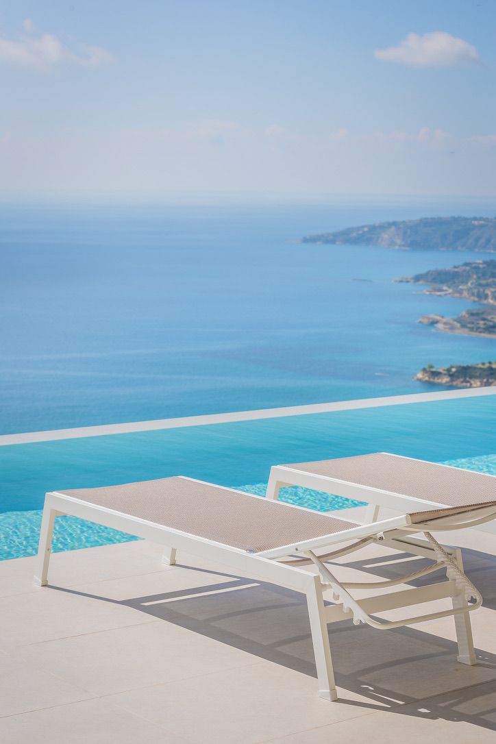 Two loungers beside a villa pool above the sea
